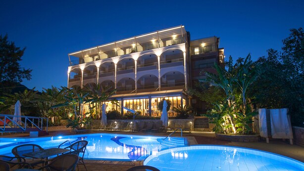 A hotel with a swimming pool, outdoor seating, and a multi-story structure with balconies. - Paradise Lost Hotel-Apartments (Nafplio)