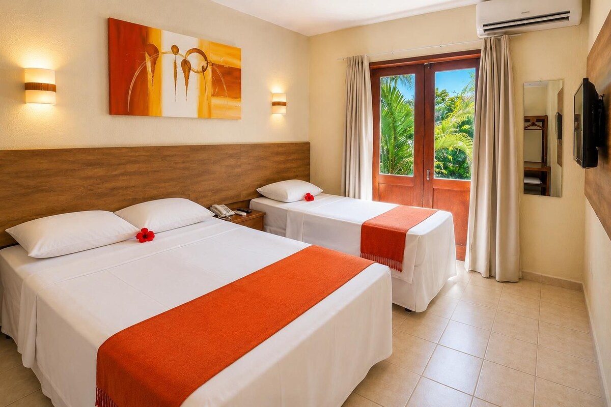 Quarto de hotel com duas camas, cabeceira de madeira, um quadro, telefone e vista para o verde pela janela.