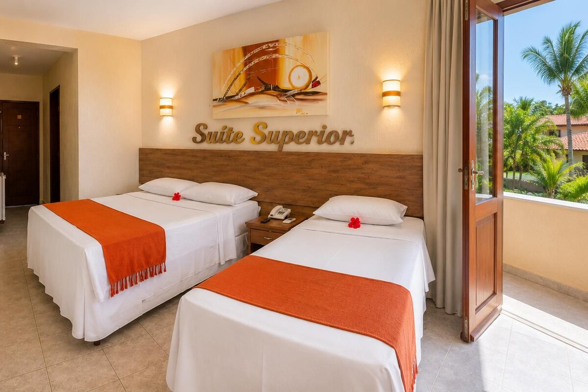 A hotel room with two beds, a wooden headboard, a painting, and a view of palm trees.