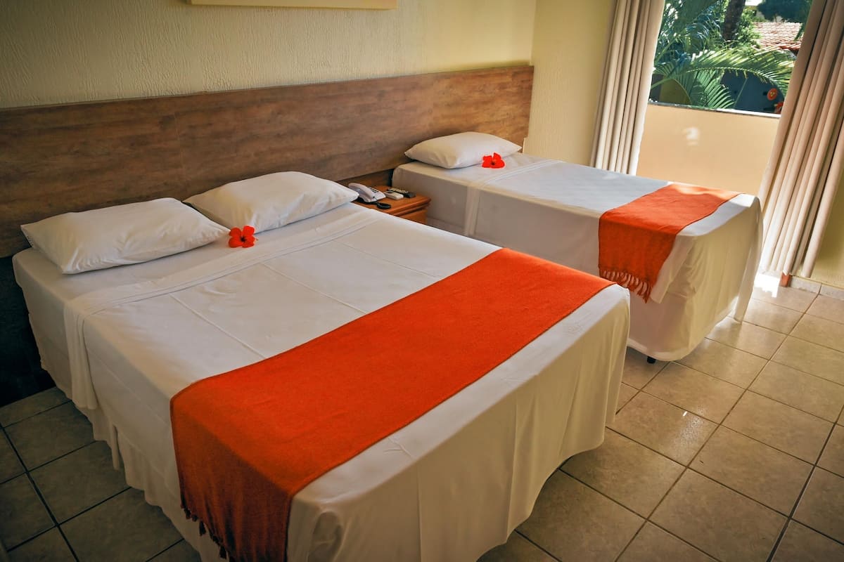 Une chambre d’hôtel avec deux lits, chacun étant équipé de draps blancs et de plaids orange.