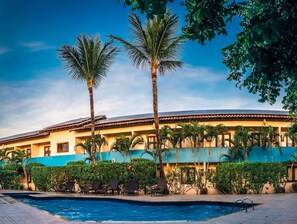 A hotel with a swimming pool, palm trees, and a blue and yellow facade. - Ayla Praia Hotel (Porto Seguro)