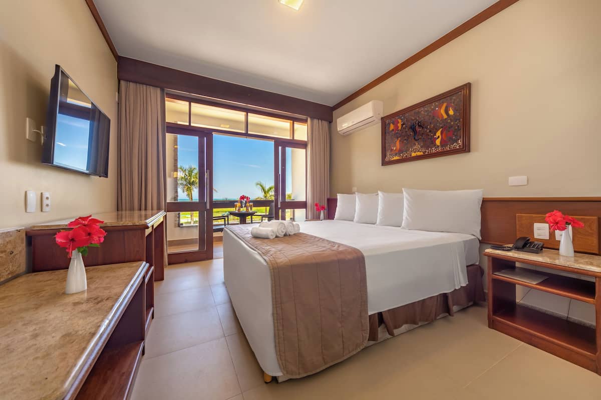 A hotel room with a bed, a desk, a chair, a TV, and a window with a view.
