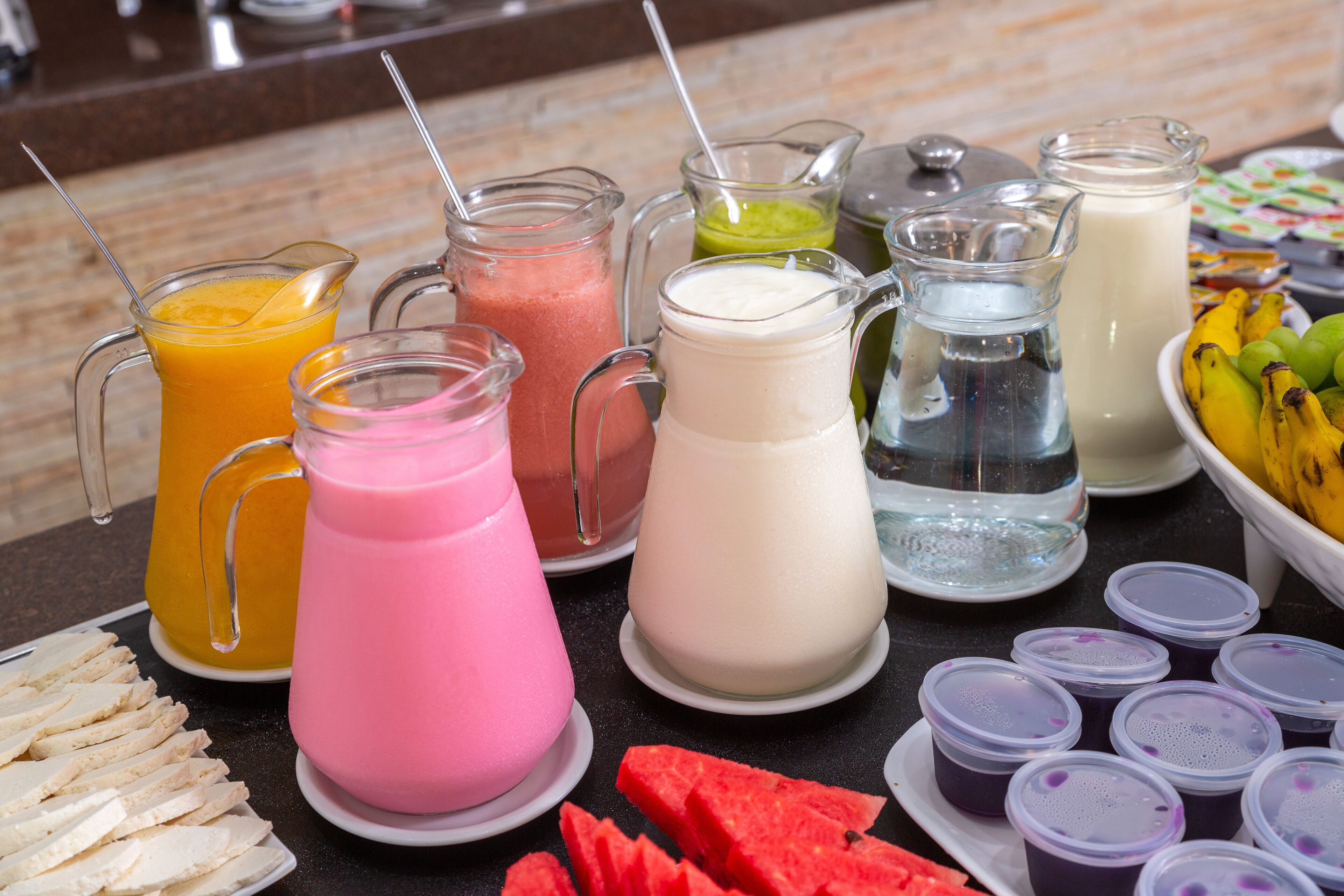 A buffet with various beverages and sliced fruits.