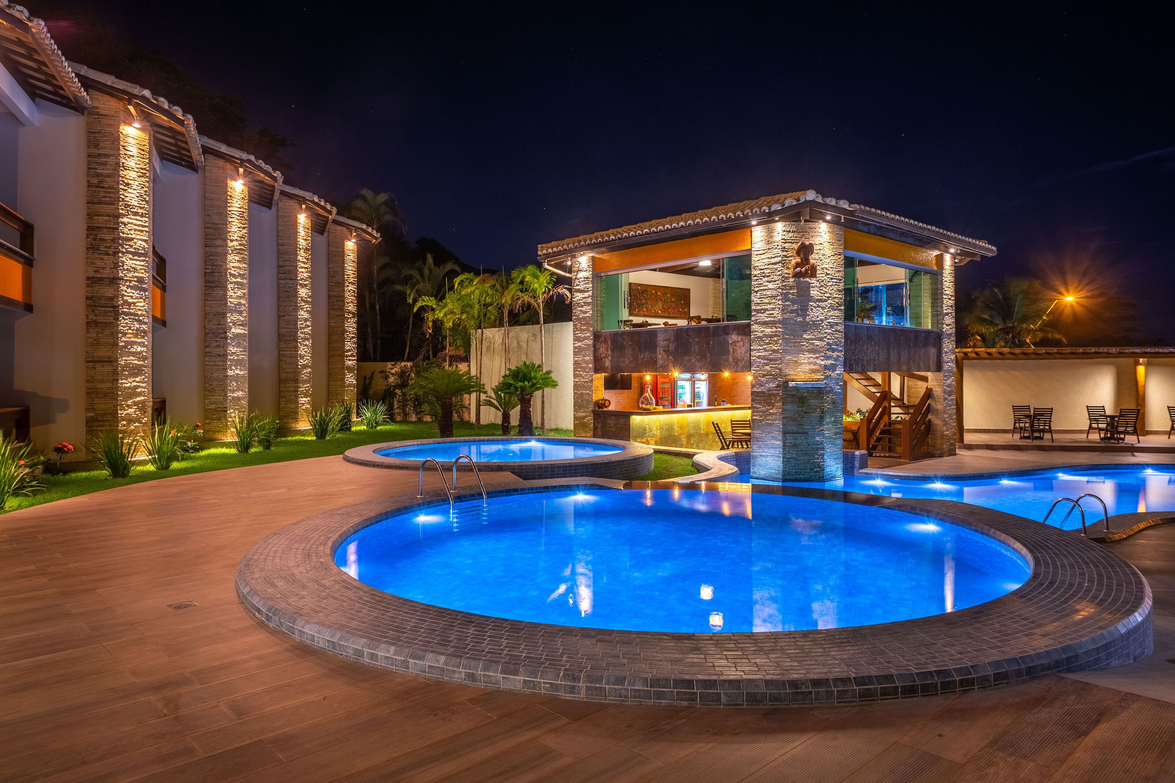 A swimming pool with a stone deck, a bar area, and a poolside seating area.