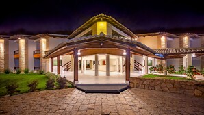 A modern hotel entrance with a covered patio, stone pillars, and a well-lit facade. - Quinta do Sol Praia Hotel (Porto Seguro)