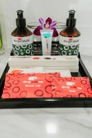 A tray with sleepwithme branded products including shampoo, conditioner, shower gel, dental kit, cotton buds, and a shower cap.