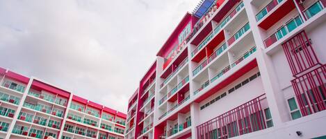 A multi-story hotel with balconies and a red and white color scheme.