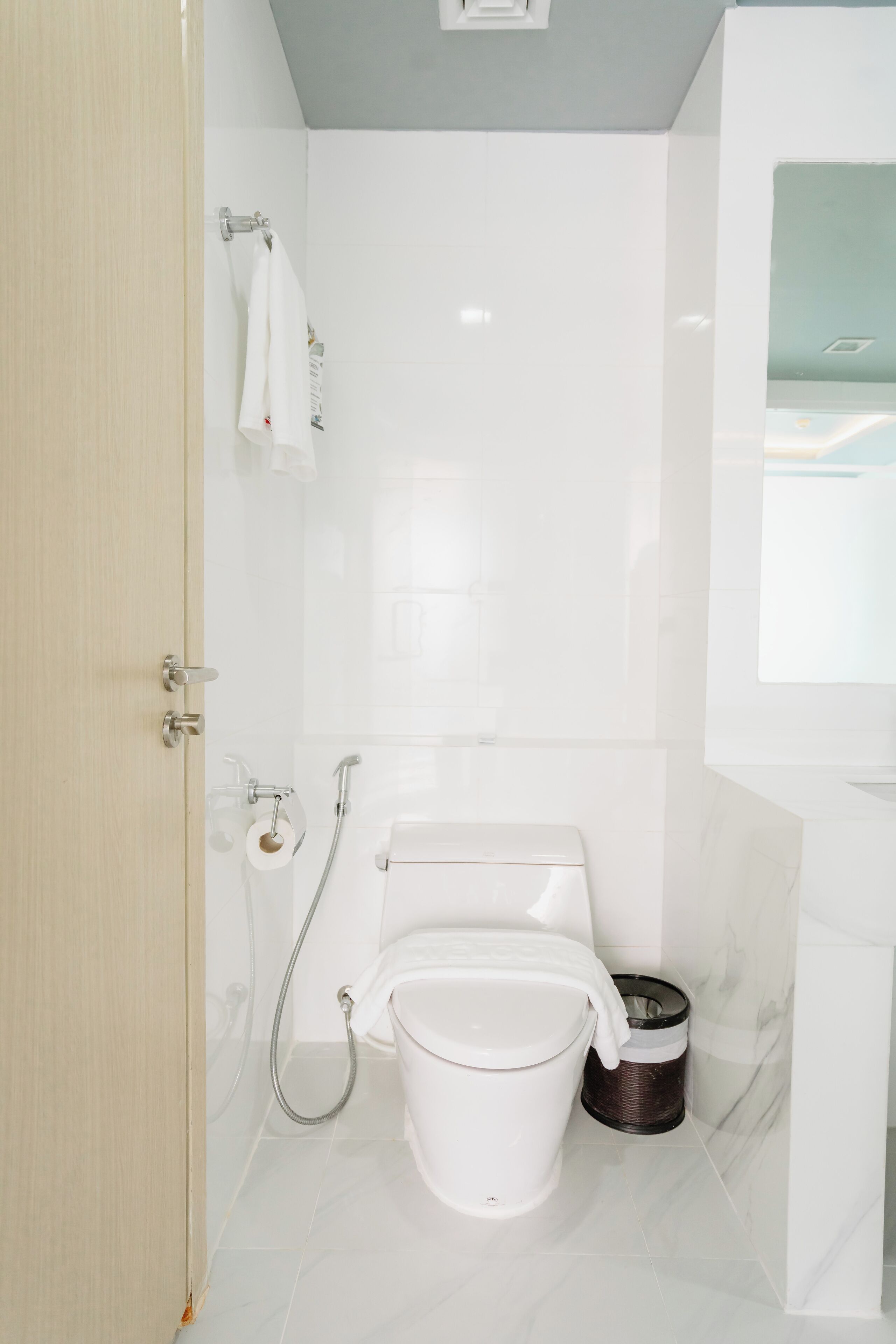A modern bathroom with a toilet, bidet, and a trash bin.