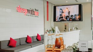 A hotel reception area with a sofa, a TV screen, a reception desk, and a 'Used Glass' sign. - SLEEP WITH ME HOTEL design hotel @ patong (Patong)