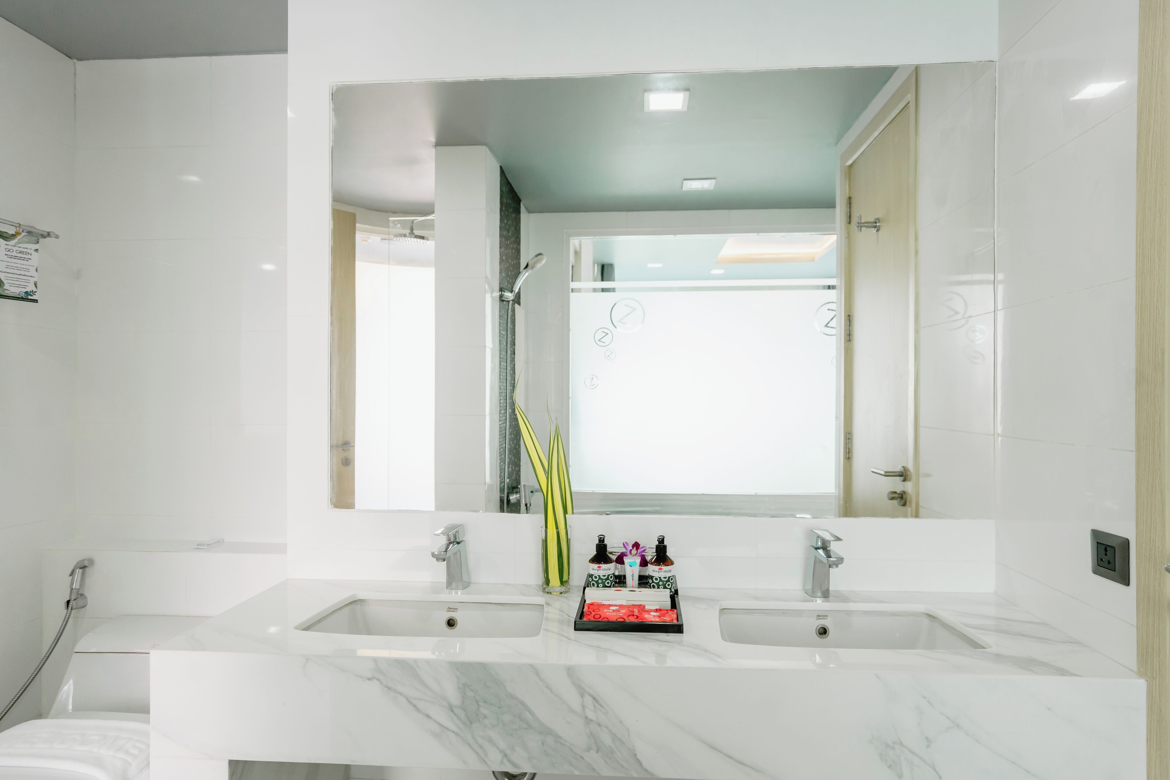 A modern bathroom with two sinks, a large mirror, and a shower area.