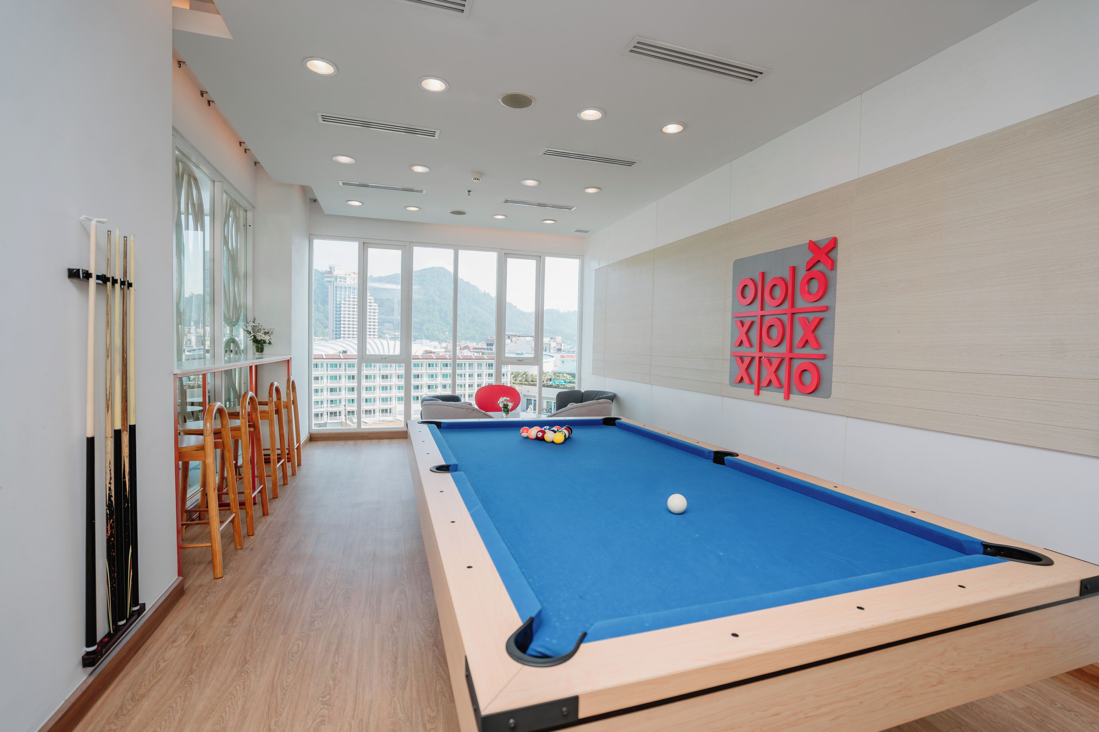 A pool table with a blue felt surface, wooden chairs, and a red ball in the center.