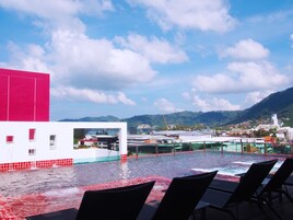A rooftop pool with a view of a cityscape and mountains in the background.