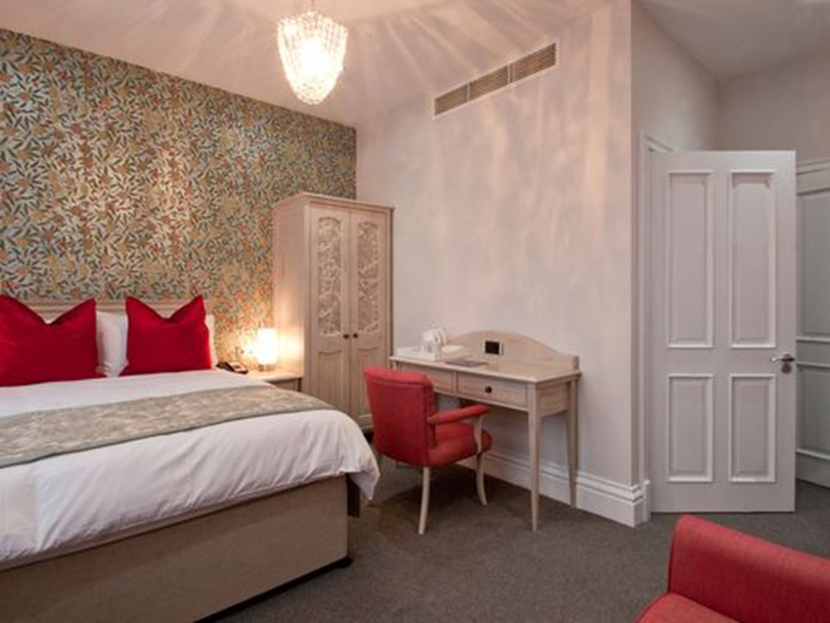 Une chambre à coucher avec un lit, un bureau, une chaise et une armoire.