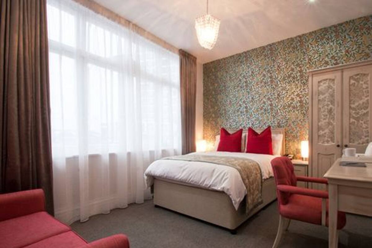 A hotel room with a bed, a desk, a chair, and a wardrobe.