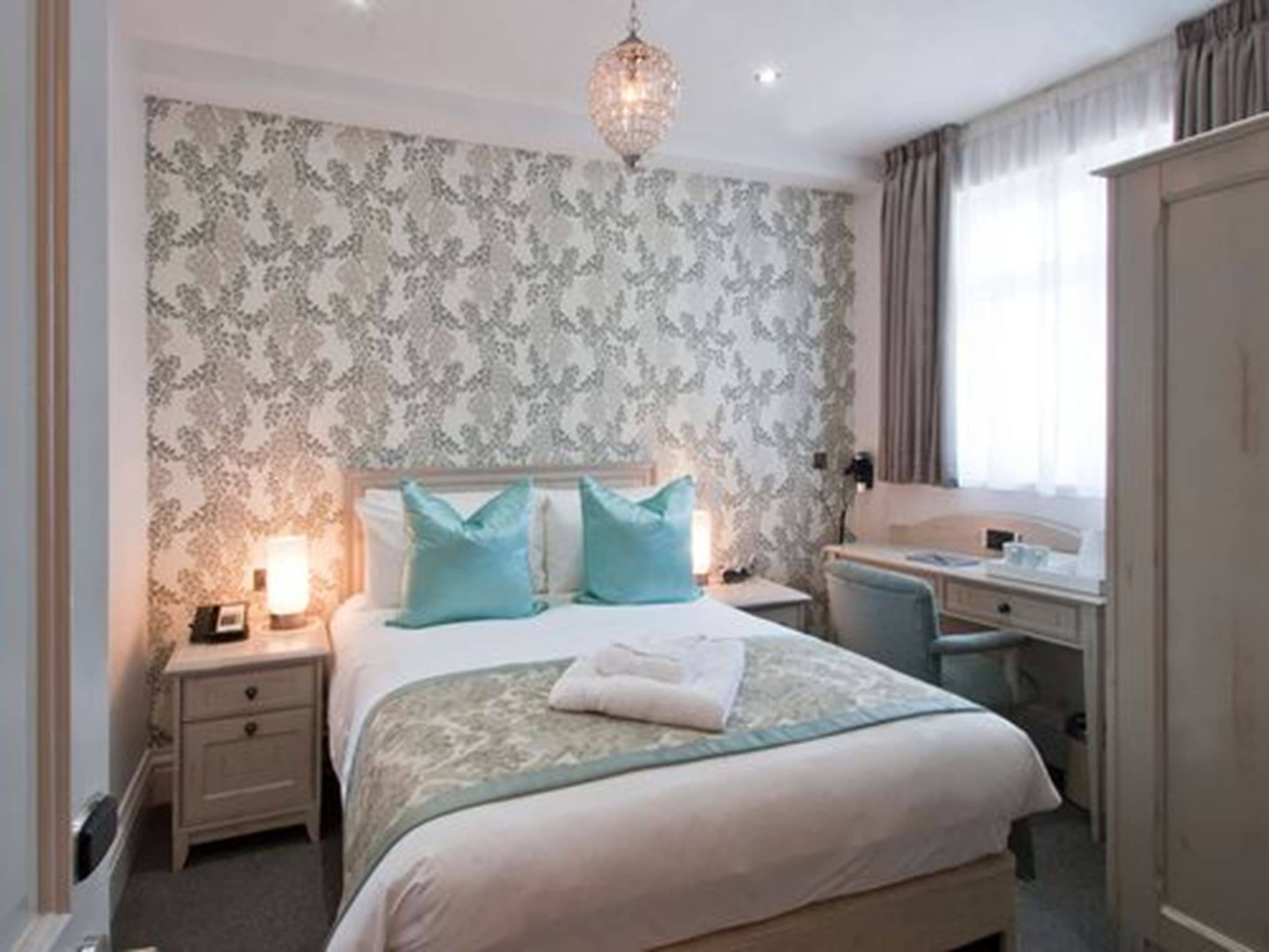 Een hotelkamer met een bed, nachtkastjes, een bureau en een stoel.