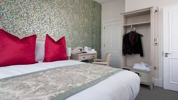 A neatly arranged hotel room with a bed, a bedside table, a chair, and a wardrobe.