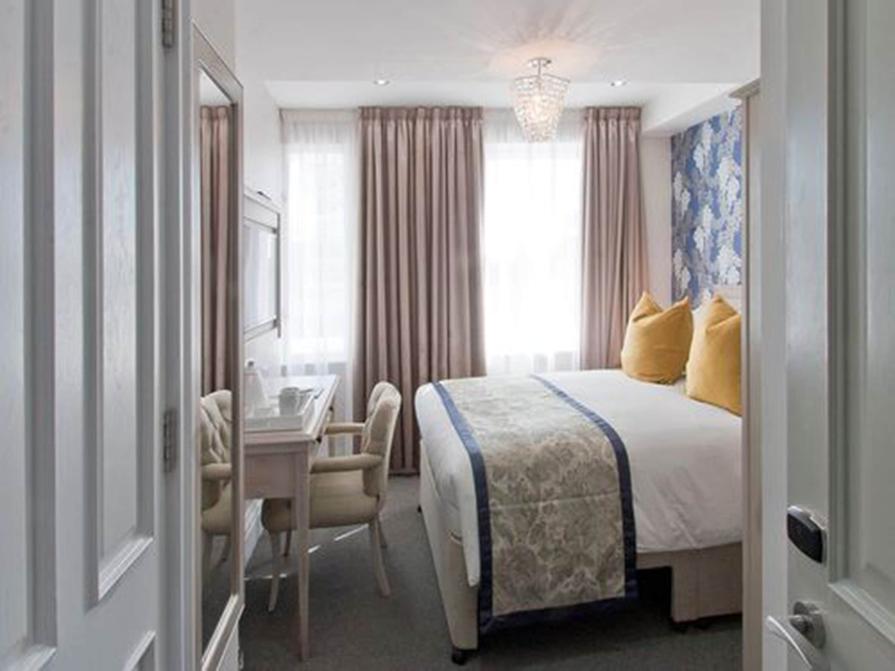 A hotel room with a bed, a desk, and a chair.