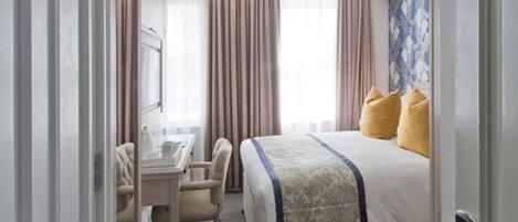 A hotel room with a bed, a desk, and a chair.