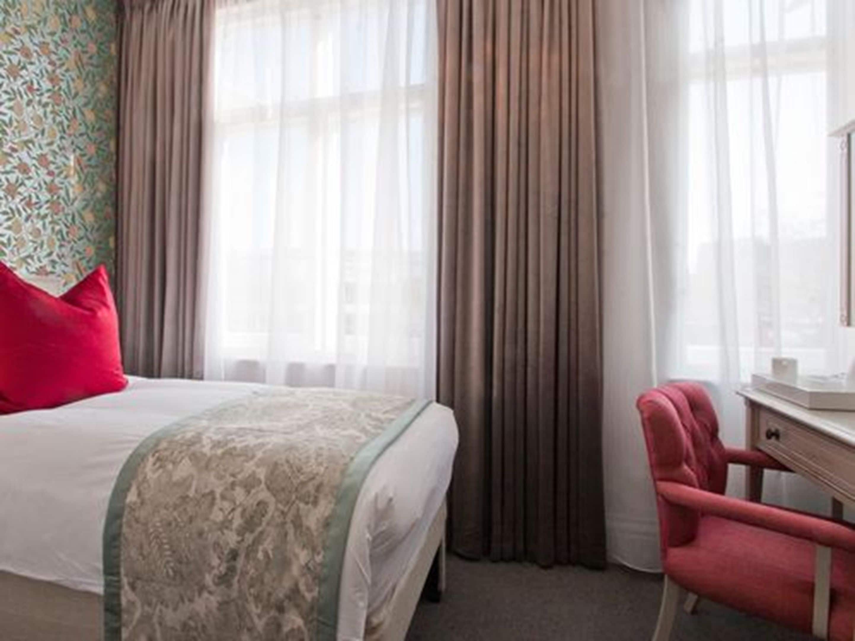 Una habitación de hotel con una cama, un escritorio y una silla.