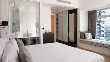 Une chambre d’hôtel moderne dotée d’un grand lit, d’une table de chevet, d’un miroir, d’une armoire et d’une fenêtre donnant sur la ville.