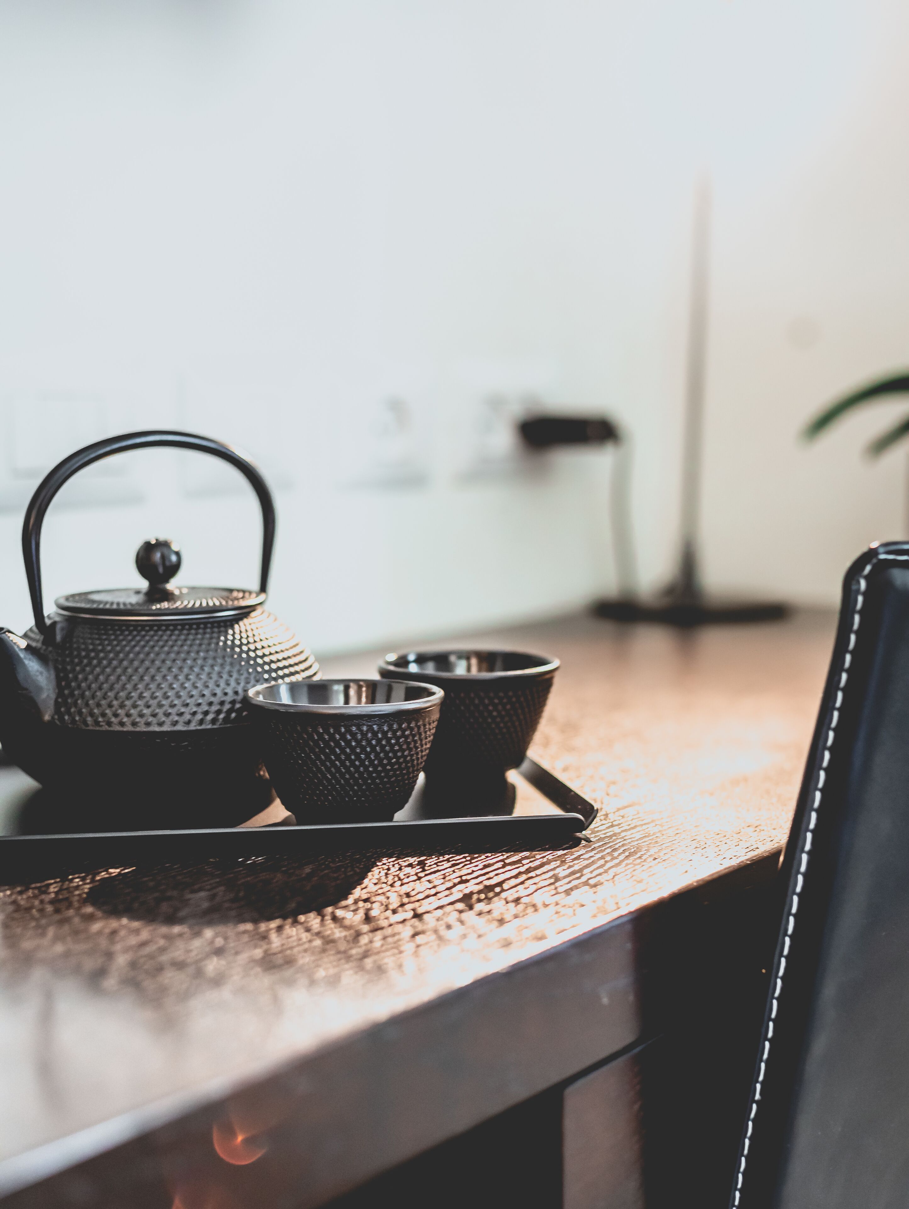 A kitchen counter with a kettle, two cups, and a tray.