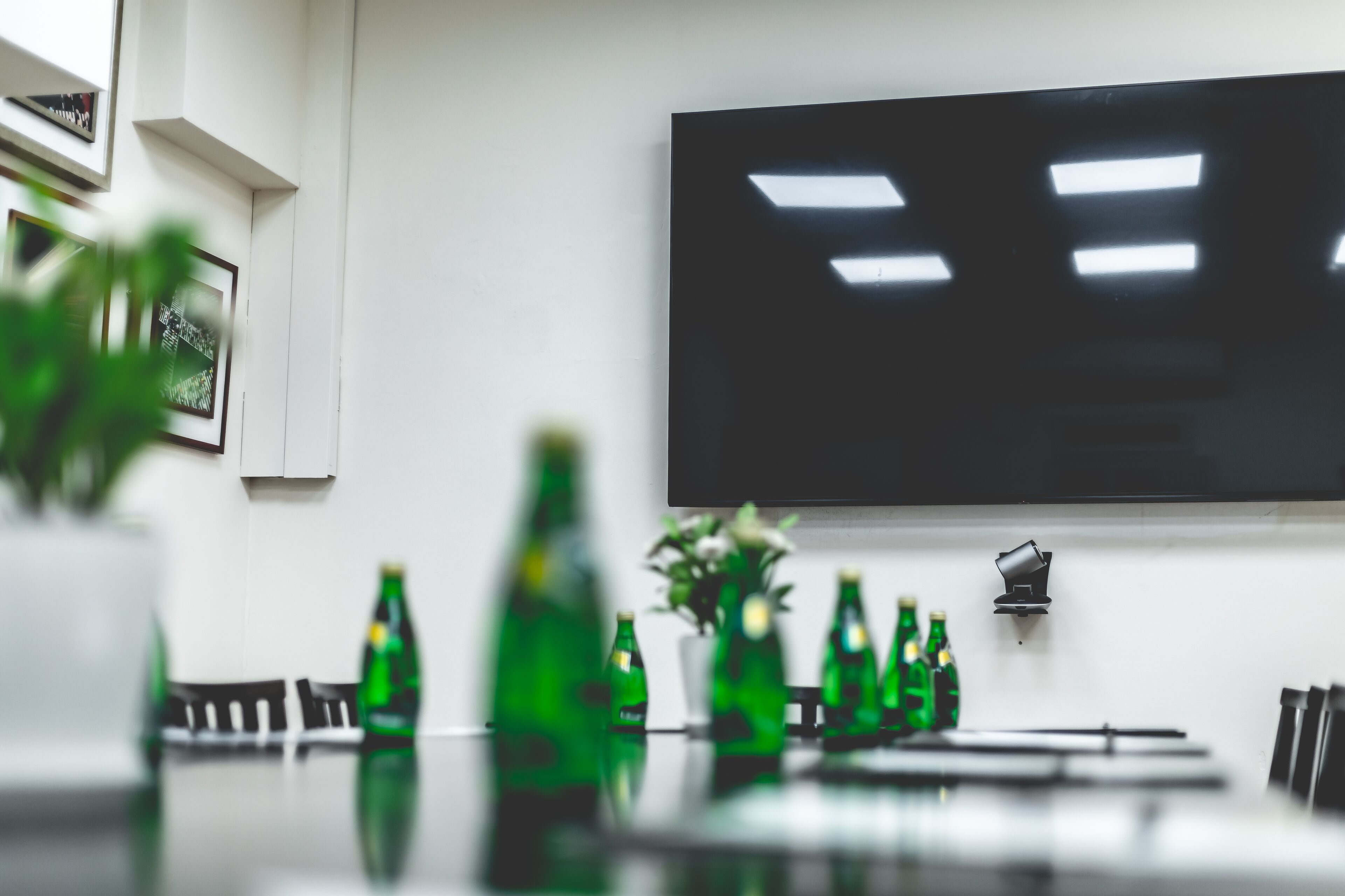 A conference room with a long table, several chairs, and green bottles on the table.