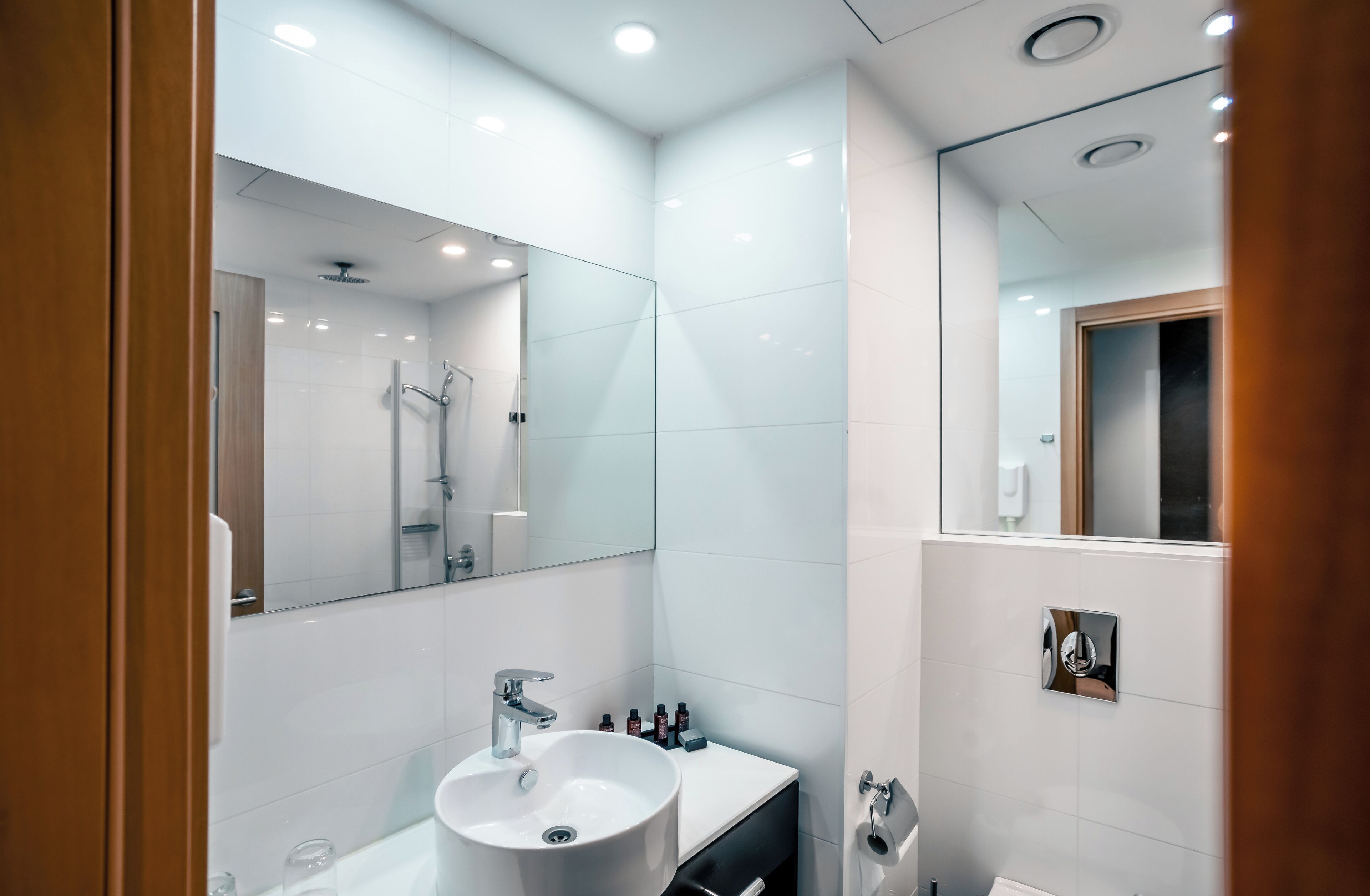 Een moderne badkamer met een grote spiegel, een wastafel en een douche.