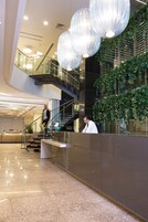 Una hall moderna con una scala in vetro, una reception e lampadari a sospensione.
