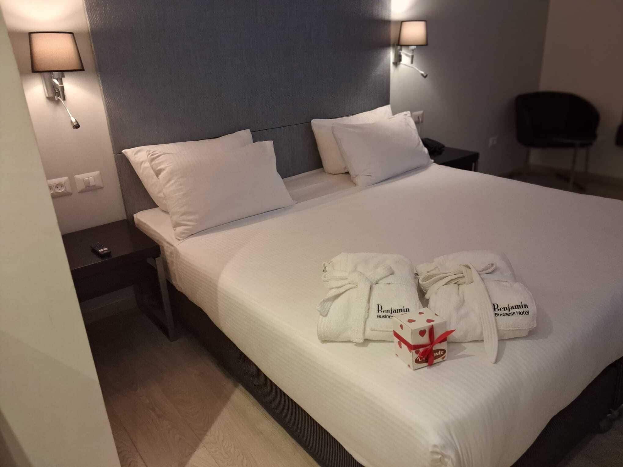 Siististi pedattu sänky valkoisilla lakanoilla, kaksi tyynyä ja kaksi pyyhettä, joissa on hotellin logo: »Benjamin Business Hotel». Sängyn vieressä on kaksi lamppua ja yöpöytä, jossa on kaukosäädin.