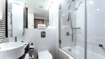 Un baño moderno con un lavamanos grande, inodoro y ducha a ras de suelo.