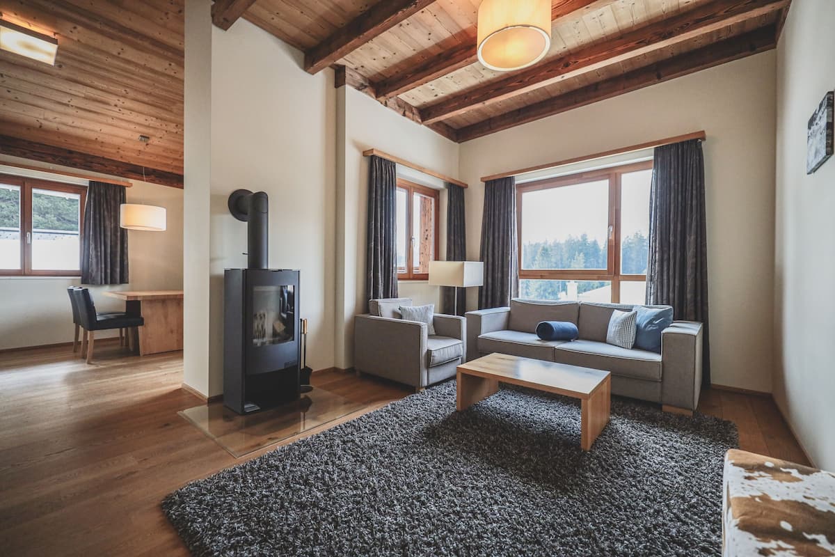 A modern living room with a fireplace, two sofas, a coffee table, and a dining area with a table and chairs.