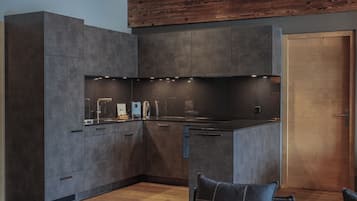 A modern kitchen with dark cabinetry, a built-in oven, and a wooden ceiling.
