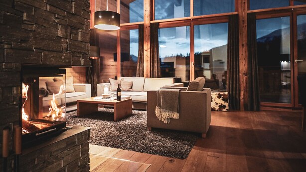 Un salón acogedor con chimenea, un sofá, una mesa de centro y un ventanal con vistas al exterior.