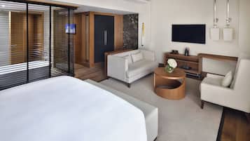 Ein modernes Hotelzimmer mit einem großen Bett, einer Couch, einem Fernseher und einem Holzkasten.