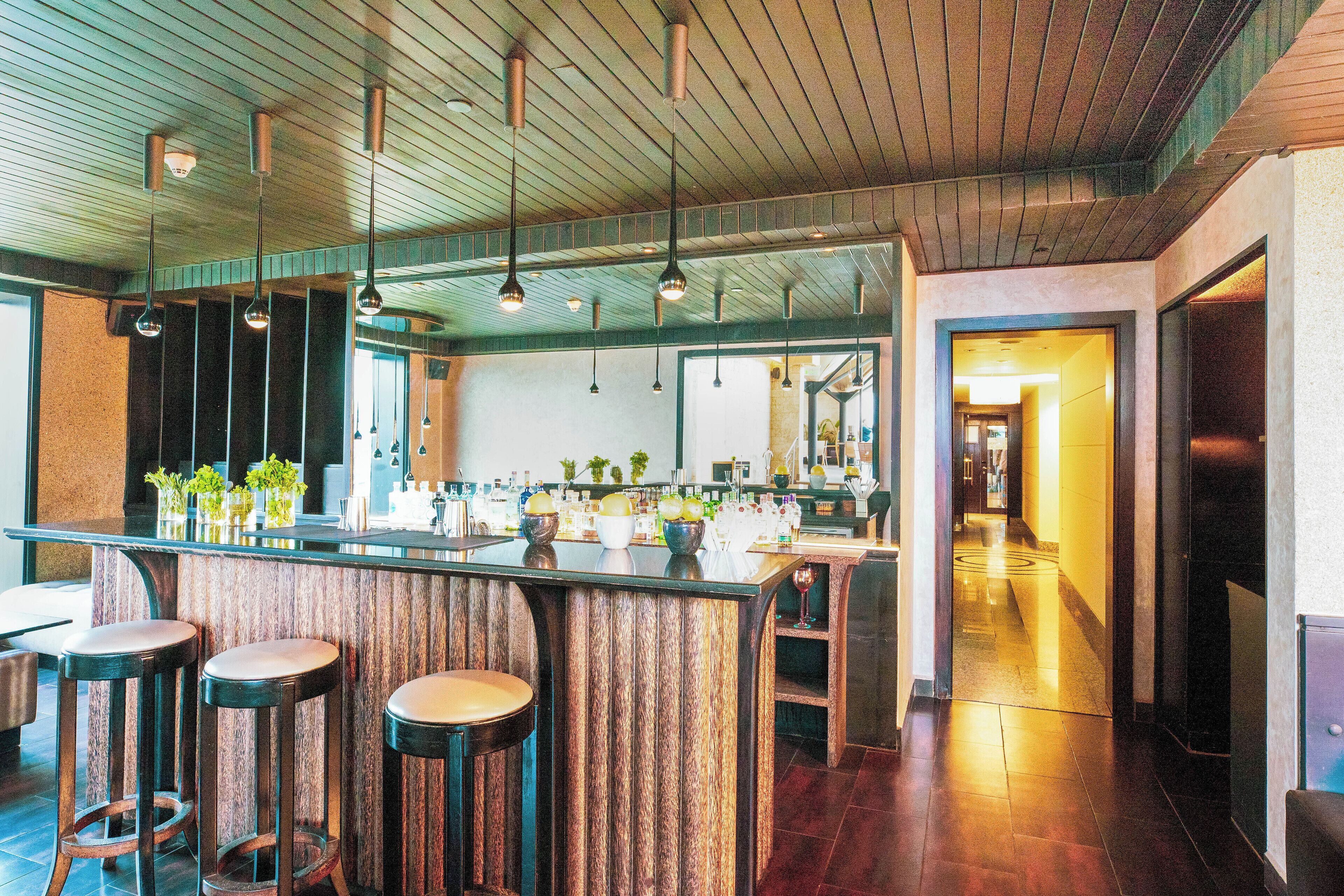 A bar area with stools, pendant lighting, and a counter with various items.