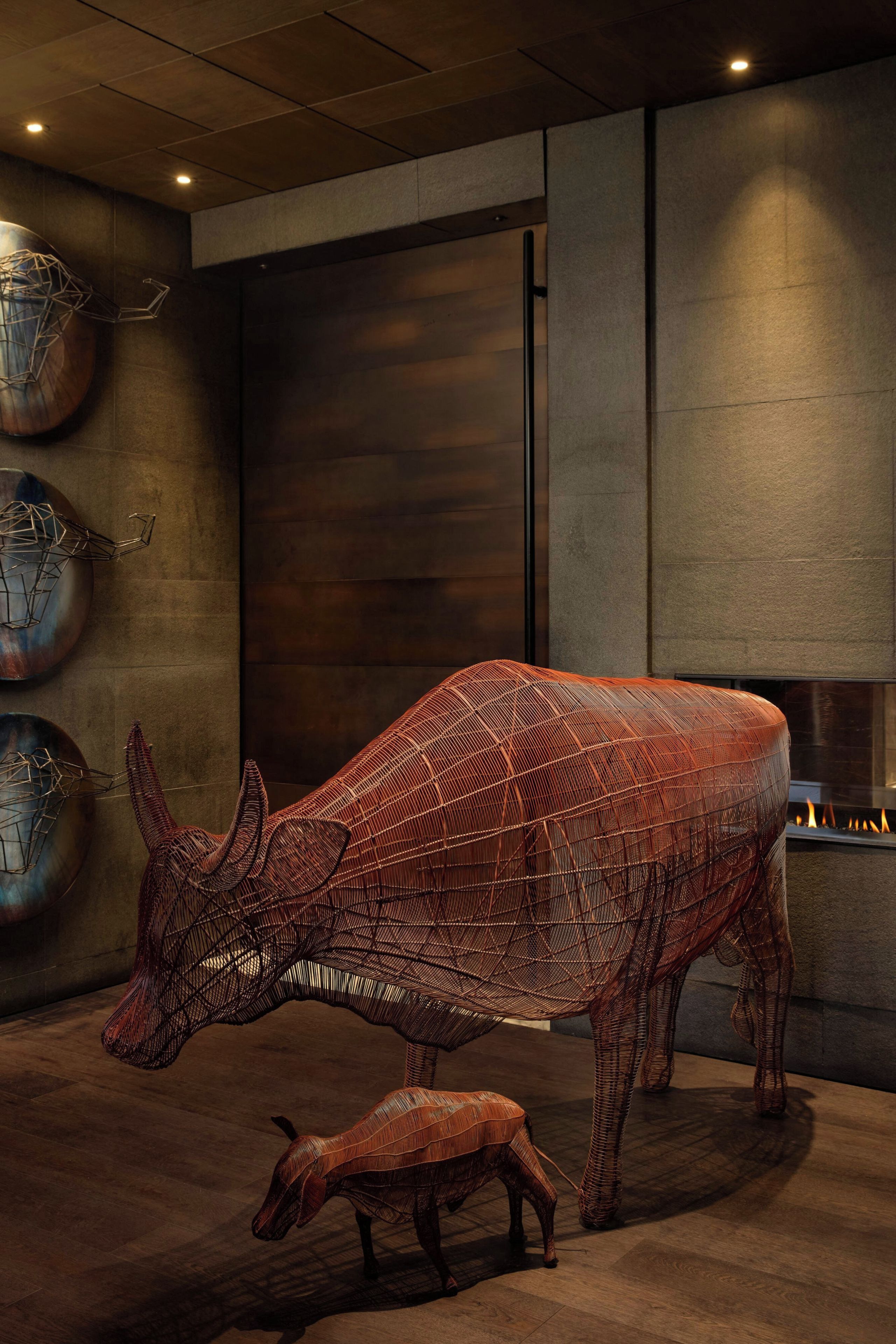 Ein modernes Interieur mit einer großen, detailreichen Metallskulptur von einem Stier und seinem Kälbchen.