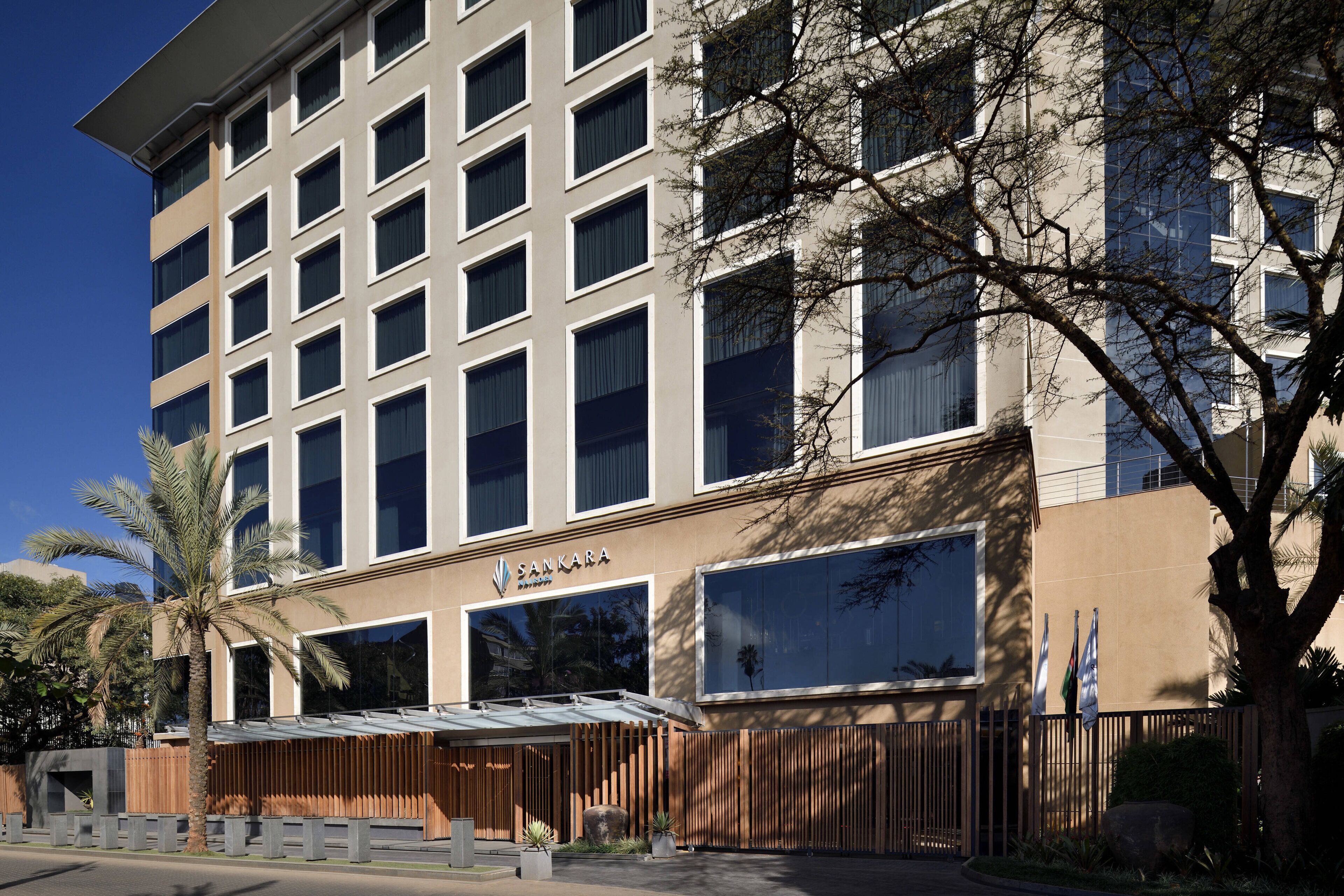 Un hôtel moderne à la façade symétrique, doté de grandes fenêtres et d’un espace d’entrée abrité.