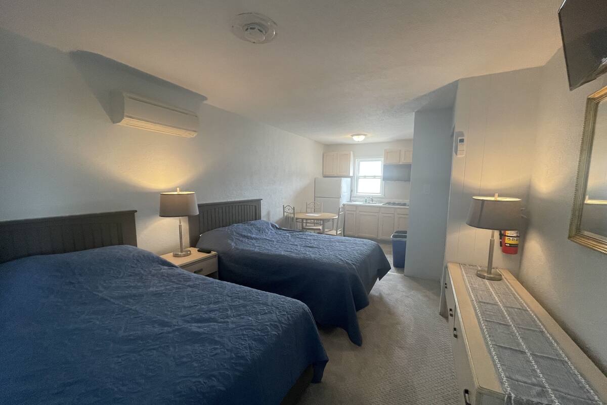 Habitació d'hotel amb dos llits, petita cuina i bany.