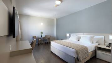 A modern hotel room with a bed, bedside tables, a desk, and a chair.