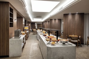 Un comedor de hotel moderno con una amplia mesa de buffet, paneles de madera y un tragaluz.