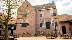 A traditional brick building with a courtyard, outdoor seating, and a staircase leading to the entrance.