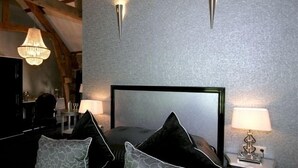 A bedroom with a large bed, two bedside tables, a chandelier, and a textured wall.