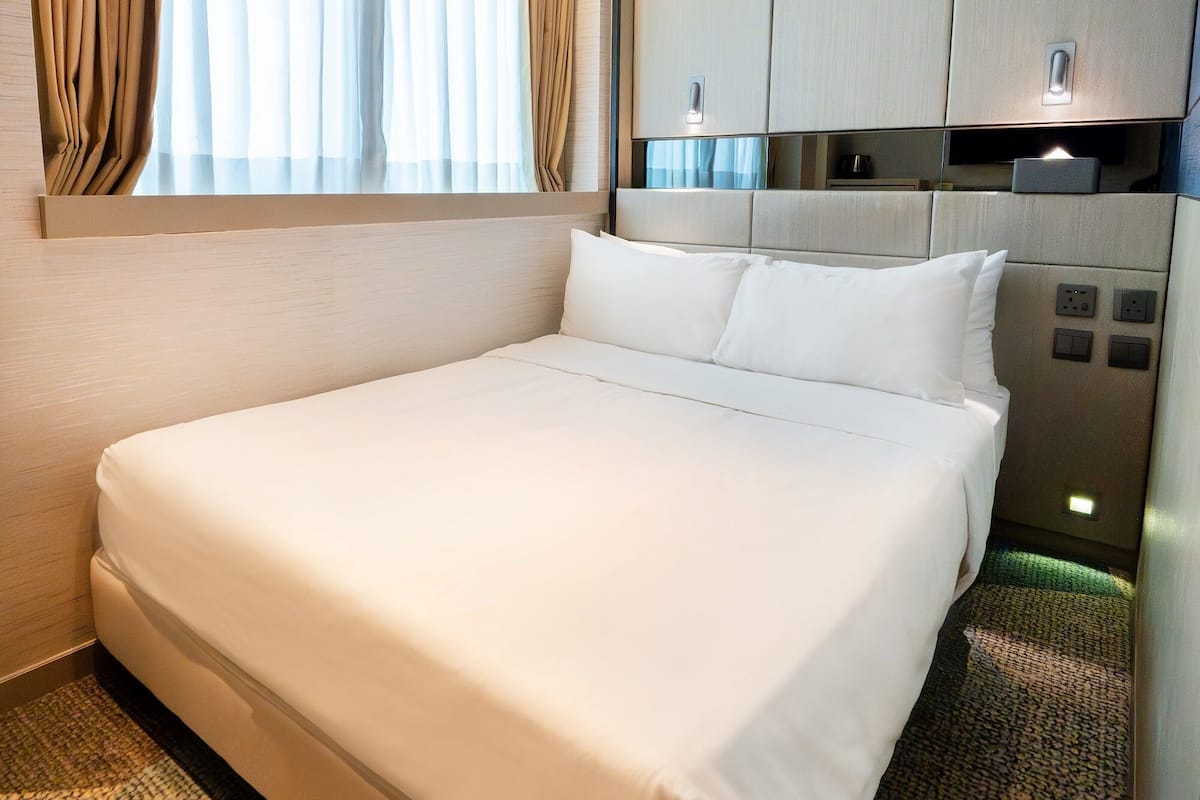 A hotel room with a large bed, a wardrobe, and a window with curtains.