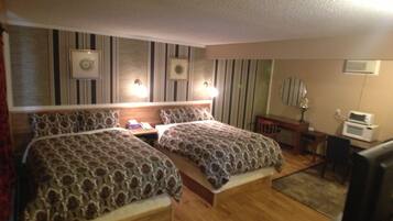 Habitación de hotel con dos camas, un escritorio, una silla, un televisor y un microondas.