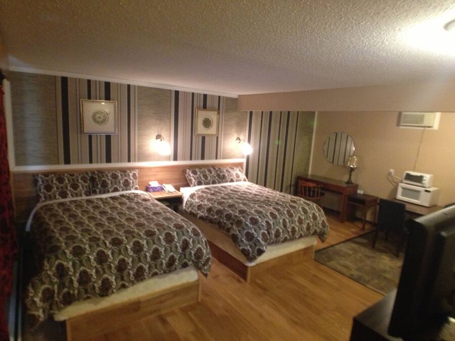 Habitación de hotel con dos camas, un escritorio, una silla, un televisor y un microondas.