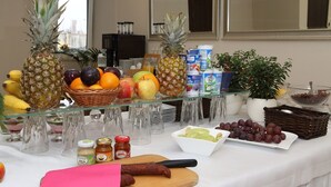 Una mesa de buffet con diversas frutas, salsas y bebidas.