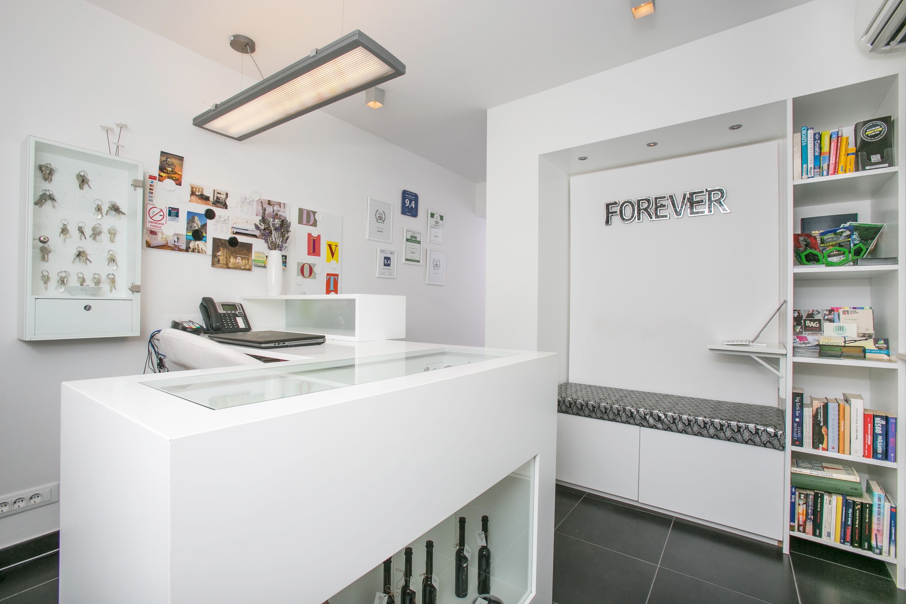 A reception area with a glass display case, a bench, and a bookshelf filled with books.