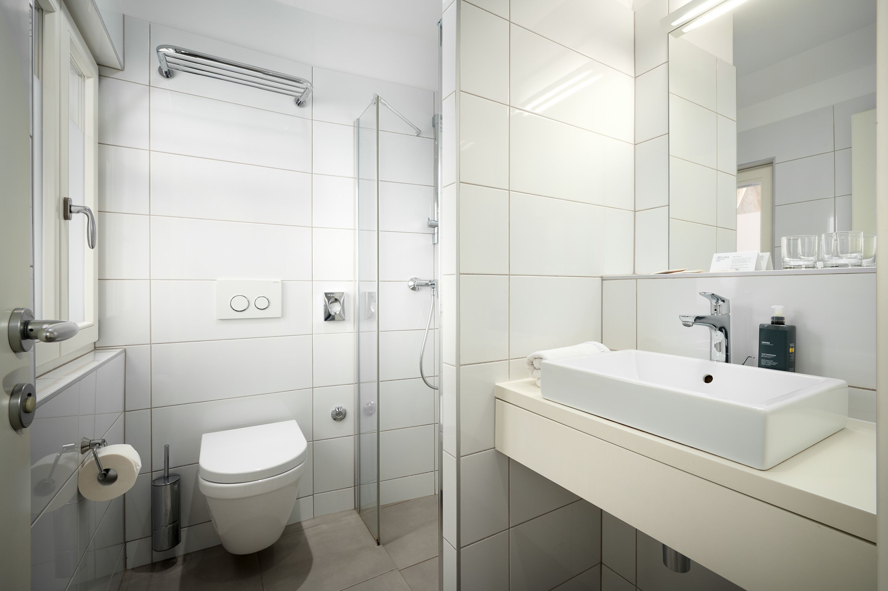 Une salle de bain moderne avec un lavabo blanc, des toilettes et une douche à parois de verre.