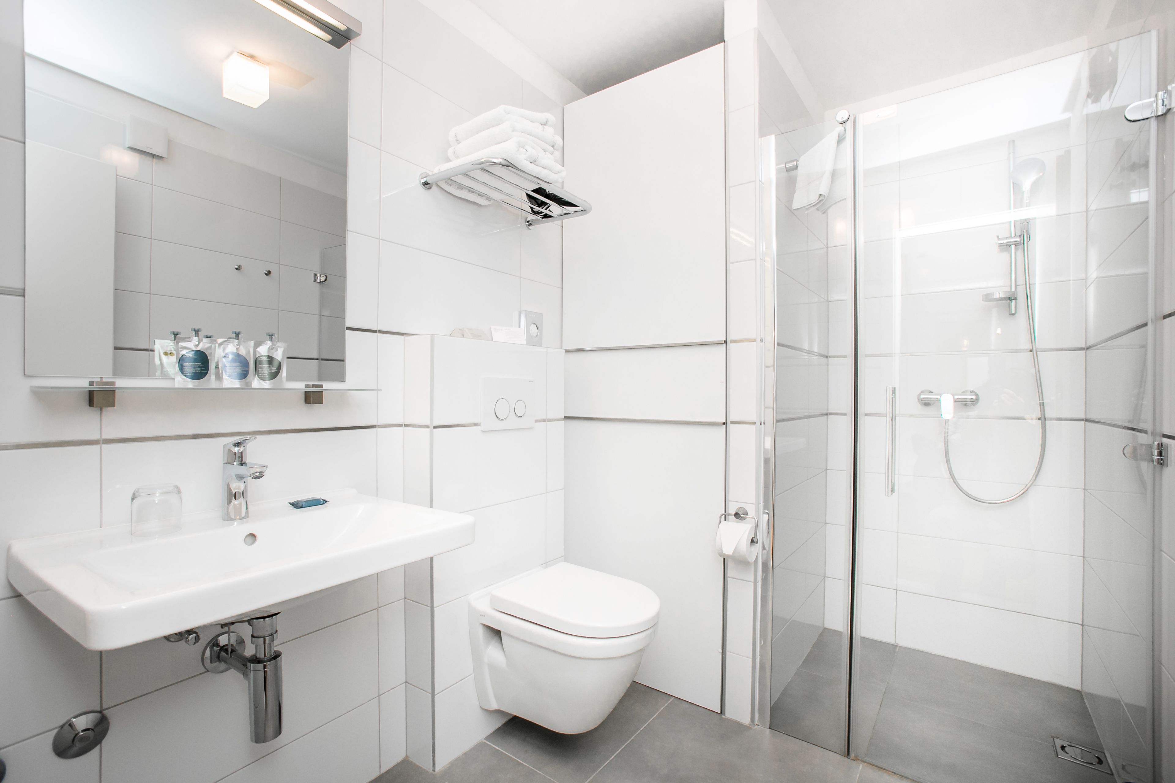 A modern bathroom with a white sink, toilet, and glass shower enclosure.