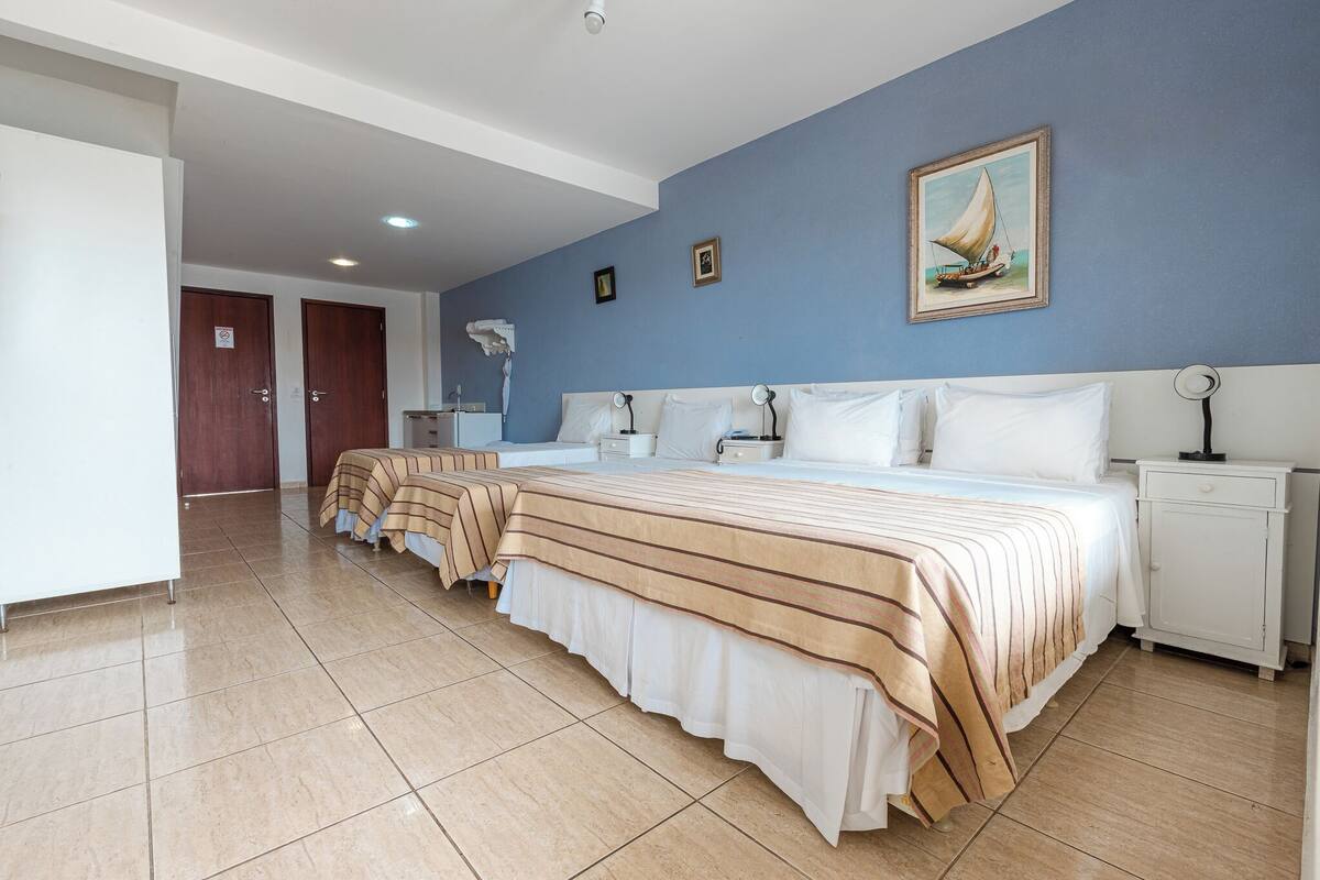 Ein Hotelzimmer mit einem großen Bett, Nachttischen, einer Lampe und einem Gemälde an der Wand.